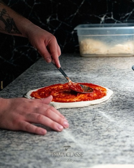 Stesura del pomodoro sull&rsquo;impasto &mdash; Prima Classe, scatto di Giesse Agency.